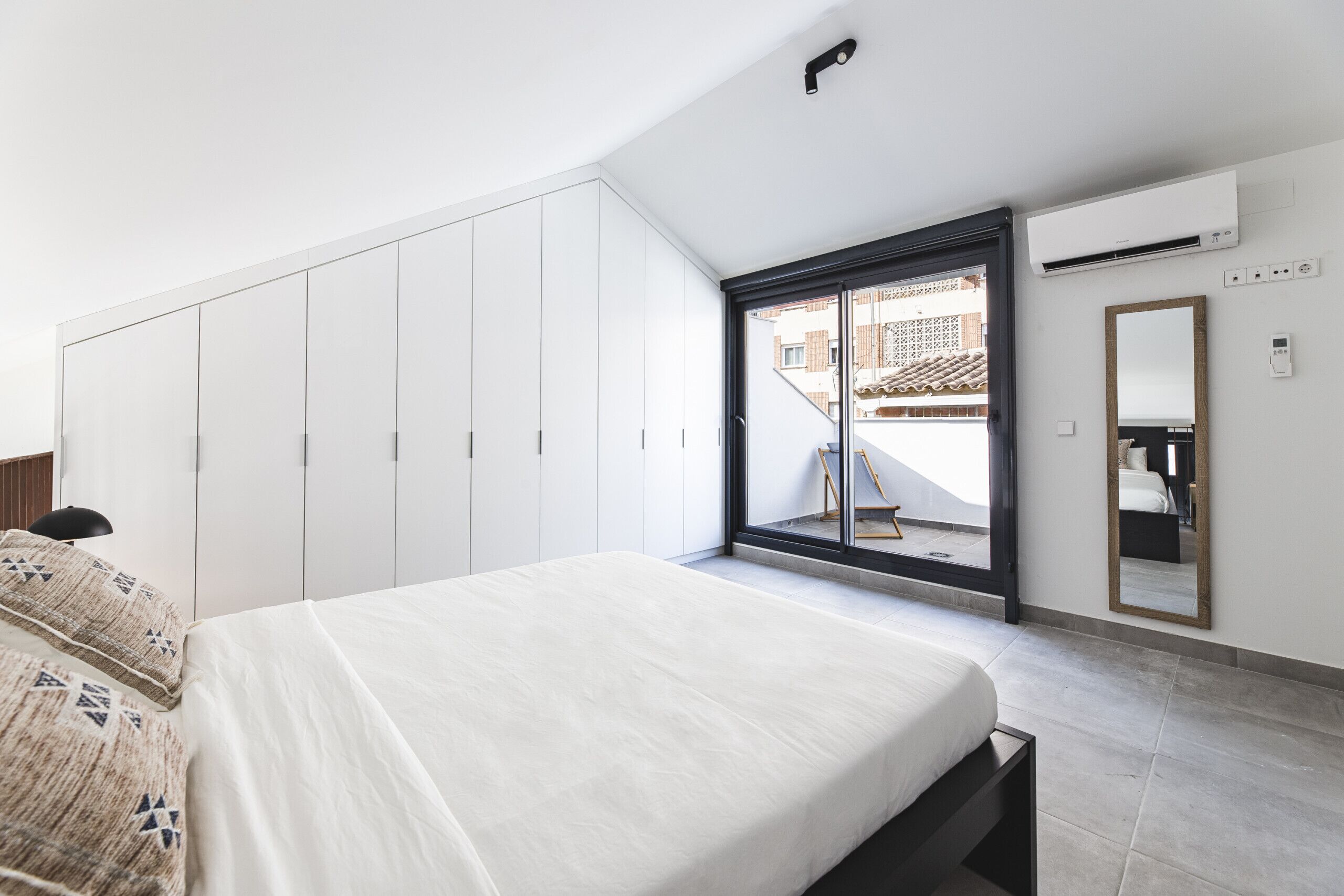 Un dormitorio con cama, armario y puerta corredera que da a un balcón.