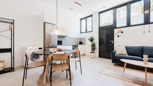 A modern kitchen with a dining area, a sofa, and a potted plant. - Valencia Apartments by Olala Homes (València)