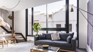 A modern living room with a sofa, coffee table, and a staircase. - Valencia Apartments by Olala Homes (València)
