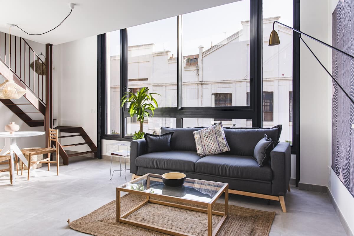A modern living room with a sofa, coffee table, and a staircase.