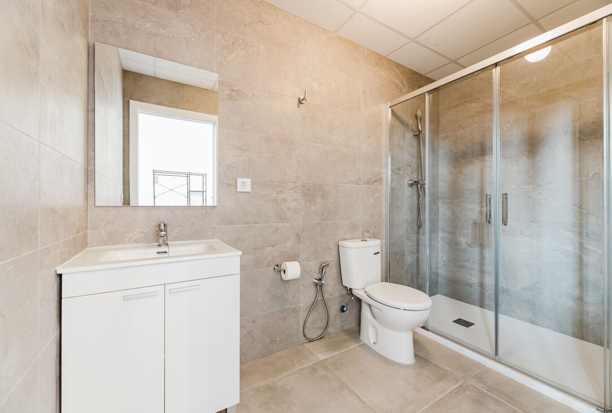 A bathroom with a shower, toilet, sink, and a mirror.