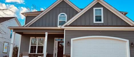 A two-story house with a garage, a front porch, and a stone accent wall.