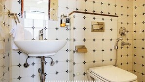 Un baño con lavamanos blanco, inodoro y ducha.