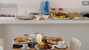Een ontbijtbuffet met gebak, fruit en drankjes.