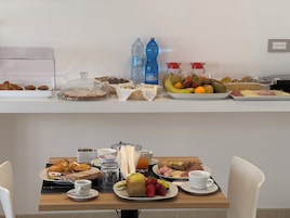 A breakfast buffet with pastries, fruits, and beverages.