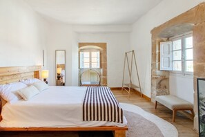 A bedroom with a bed, a bench, a swing, a mirror, and a window. - Villa Vista Ajo – 17th-Century Manor with Views, Garden, and Beach Nearby (Bareyo)