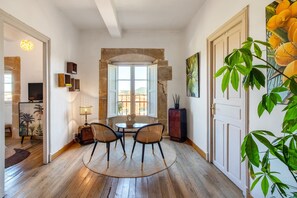 A room with a stone arch window, a round table with chairs, a lamp, and a potted plant. - Villa Vista Ajo – 17th-Century Manor with Views, Garden, and Beach Nearby (Bareyo)