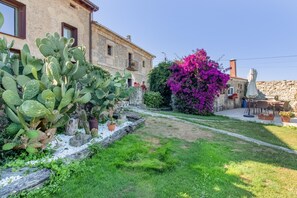 A courtyard with a cactus, a flowering tree, and a stone building. - Villa Vista Ajo – 17th-Century Manor with Views, Garden, and Beach Nearby (Bareyo)