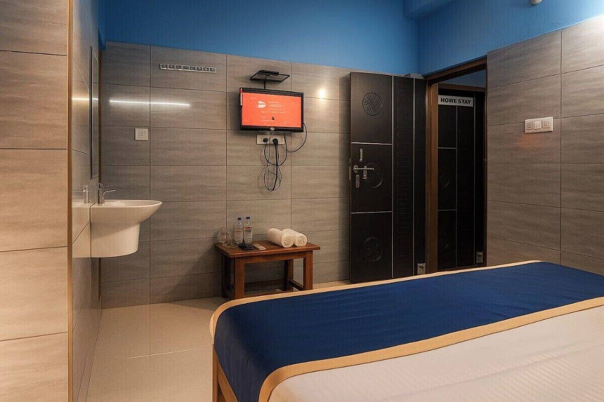 A modern hotel room with a bed, a sink, a small table with toiletries, a television, and a wardrobe.