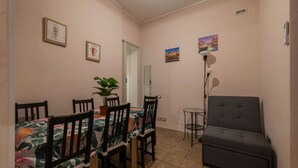 Un coin repas avec une table dressée pour quatre personnes, entourée de chaises, d ’une plante en pot et d’un canapé.