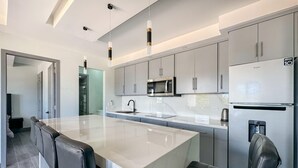 Une cuisine moderne dotée d’un grand îlot central, d’appareils électroménagers en acier inoxydable et de tabourets de bar.
