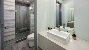 Une salle de bain moderne avec une douche à parois de verre, un lavabo blanc et un grand miroir.