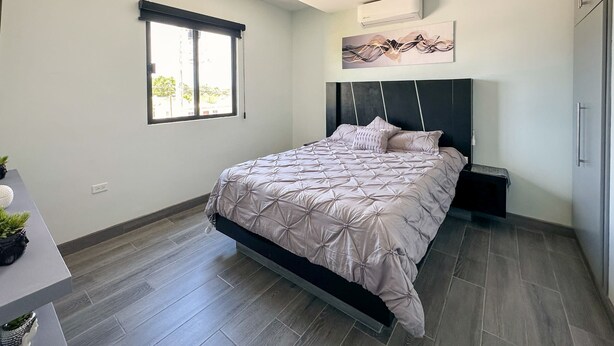 Une chambre moderne équipée d’un lit, de tables de chevet, d’une fenêtre et d’un appareil de climatisation.