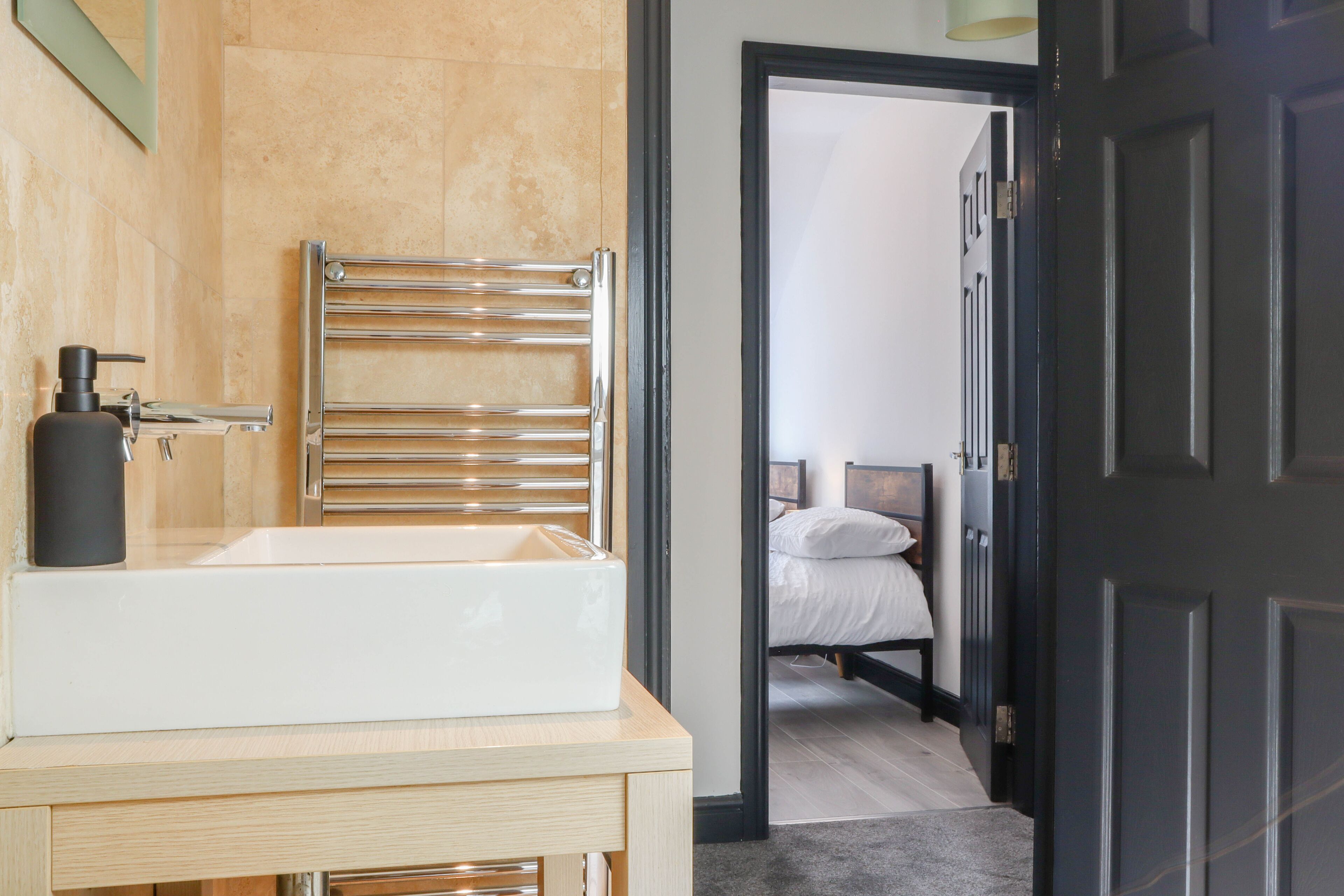 A bathroom with a large white sink, a towel rack, and a bottle of soap.