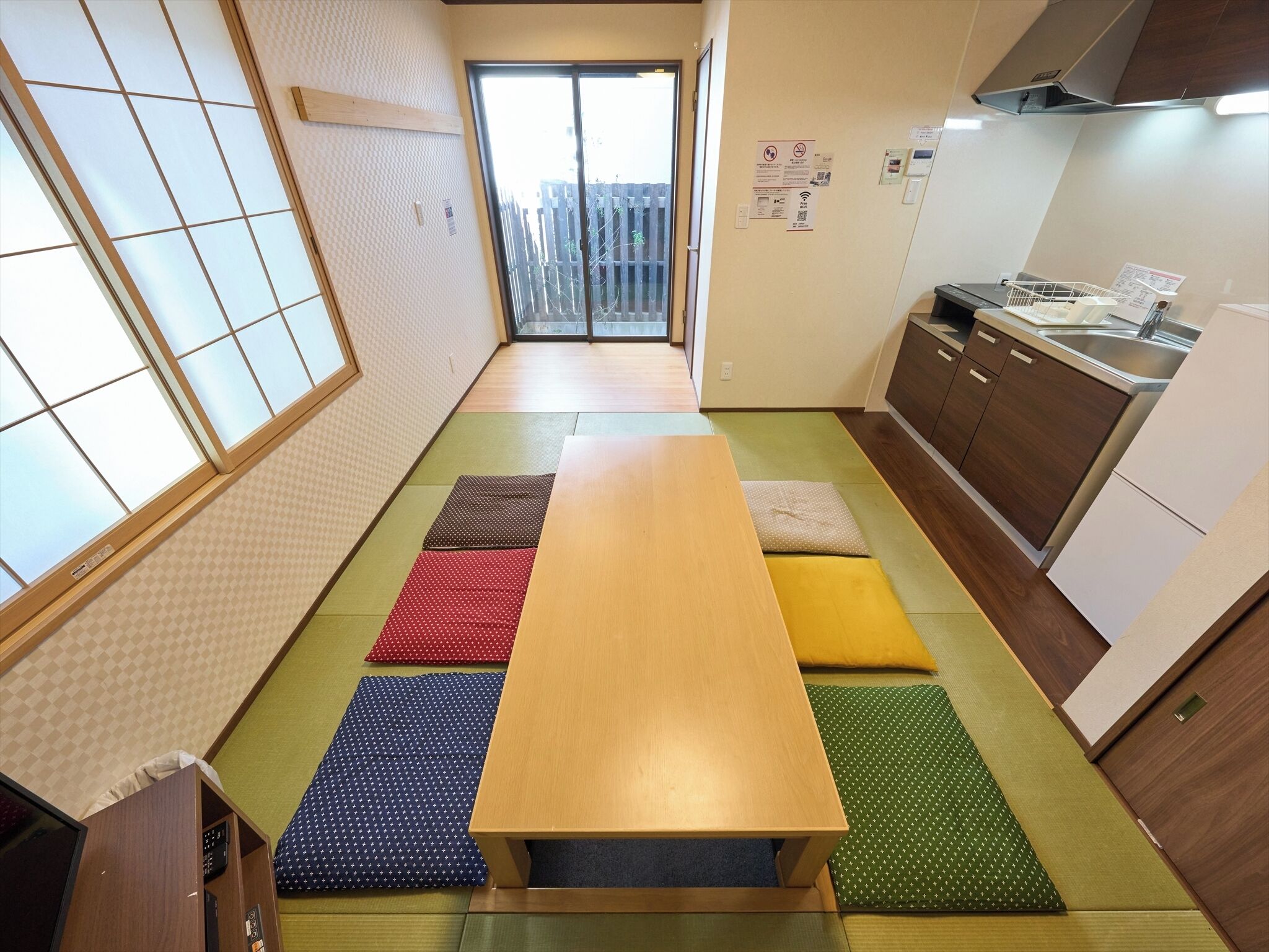 A traditional Japanese-style room with tatami mats, a wooden table, and a kitchen area with wooden cabinets and a sink.