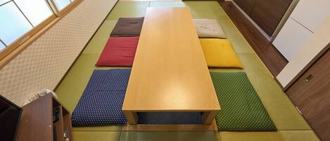 A traditional Japanese-style room with tatami mats, a wooden table, and a kitchen area with wooden cabinets and a sink.