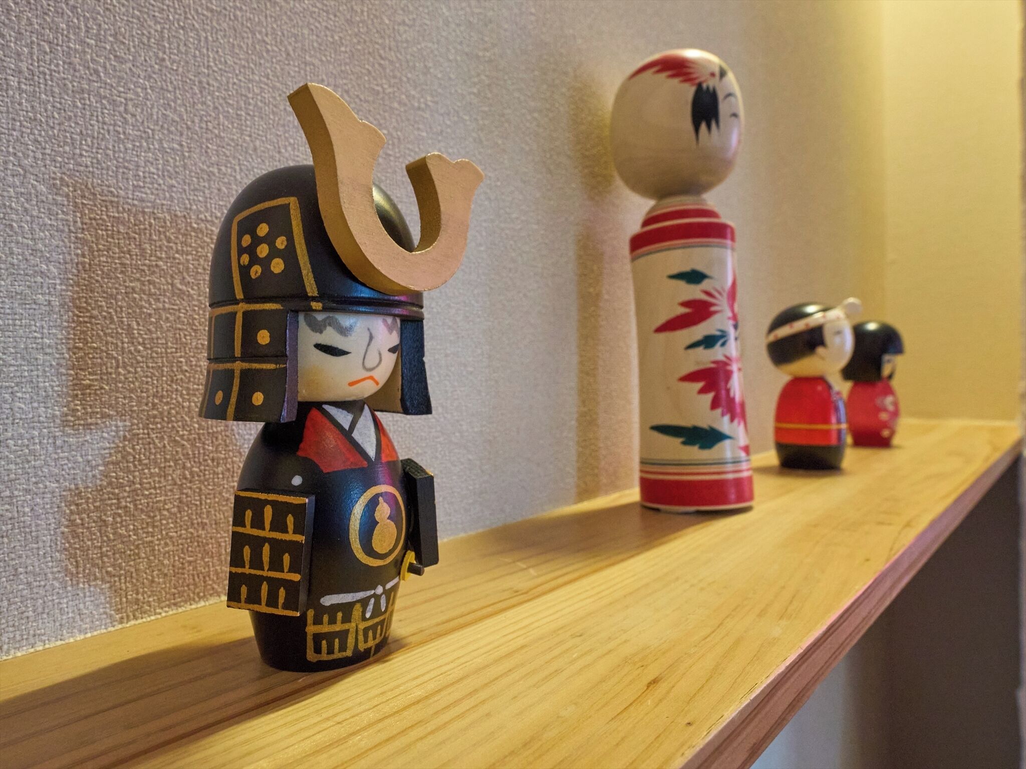 A shelf with various decorative items, including a figure with a helmet and a cylindrical container with floral patterns.