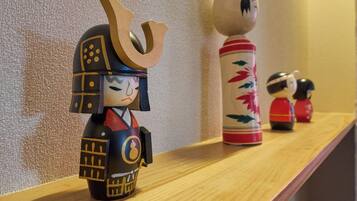 A shelf with various decorative items, including a figure with a helmet and a cylindrical container with floral patterns.