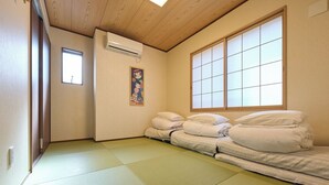 Et værelse med tatami-gulv, en futon-seng, en shoji-skærm og en aircondition-enhed.