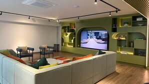 Ein modernes Wohnzimmer mit einem Ecksofa, einem Flachbildfernseher und eingebauten Regalen mit Dekorationselementen.