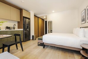 A modern hotel room with a bed, a small table, a chair, a kitchenette, and a mirror. - w Engaging Loft in the Heart of San Rafael (Mexico City)