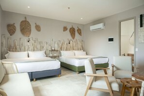 Quarto de hotel com duas camas, uma escrivaninha, uma cadeira e decoração na parede.