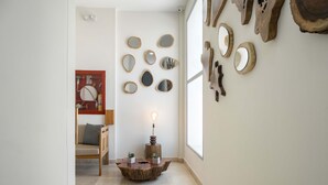 A hallway with a wooden floor, a round table with a light, and various wall-mounted mirrors. - w Ravishing 2BR in the Heart of Bocagrande (Cartagena)