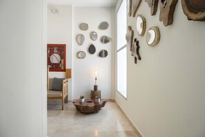 A hallway with a wooden floor, a round table with a light, and various wall-mounted mirrors. - w Ravishing 2BR in the Heart of Bocagrande (Cartagena)