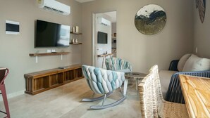 A living room with a flat-screen TV, a sofa, a rocking chair, and a wall-mounted air conditioner. - w Ravishing 2BR in the Heart of Bocagrande (Cartagena)
