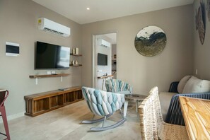 A living room with a flat-screen TV, a sofa, a rocking chair, and a wall-mounted air conditioner. - w Ravishing 2BR in the Heart of Bocagrande (Cartagena)
