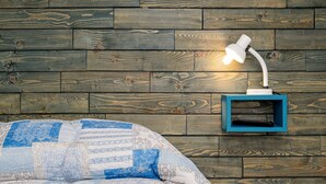 A bed with a blue and white patterned blanket, a white desk lamp, and a blue shelf against a wooden wall. - Holiday Home 'Porto San Paolo A 50 Mt Dal Mare' with Private Terrace, Wi-Fi and Air Conditioning (Porto San Paolo)