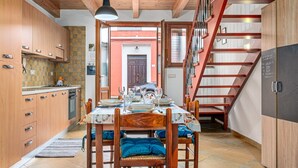 A kitchen with wooden cabinets, a dining table set with plates and glasses, and a staircase leading to an upper level. - Holiday Home 'Porto San Paolo A 50 Mt Dal Mare' with Private Terrace, Wi-Fi and Air Conditioning (Porto San Paolo)