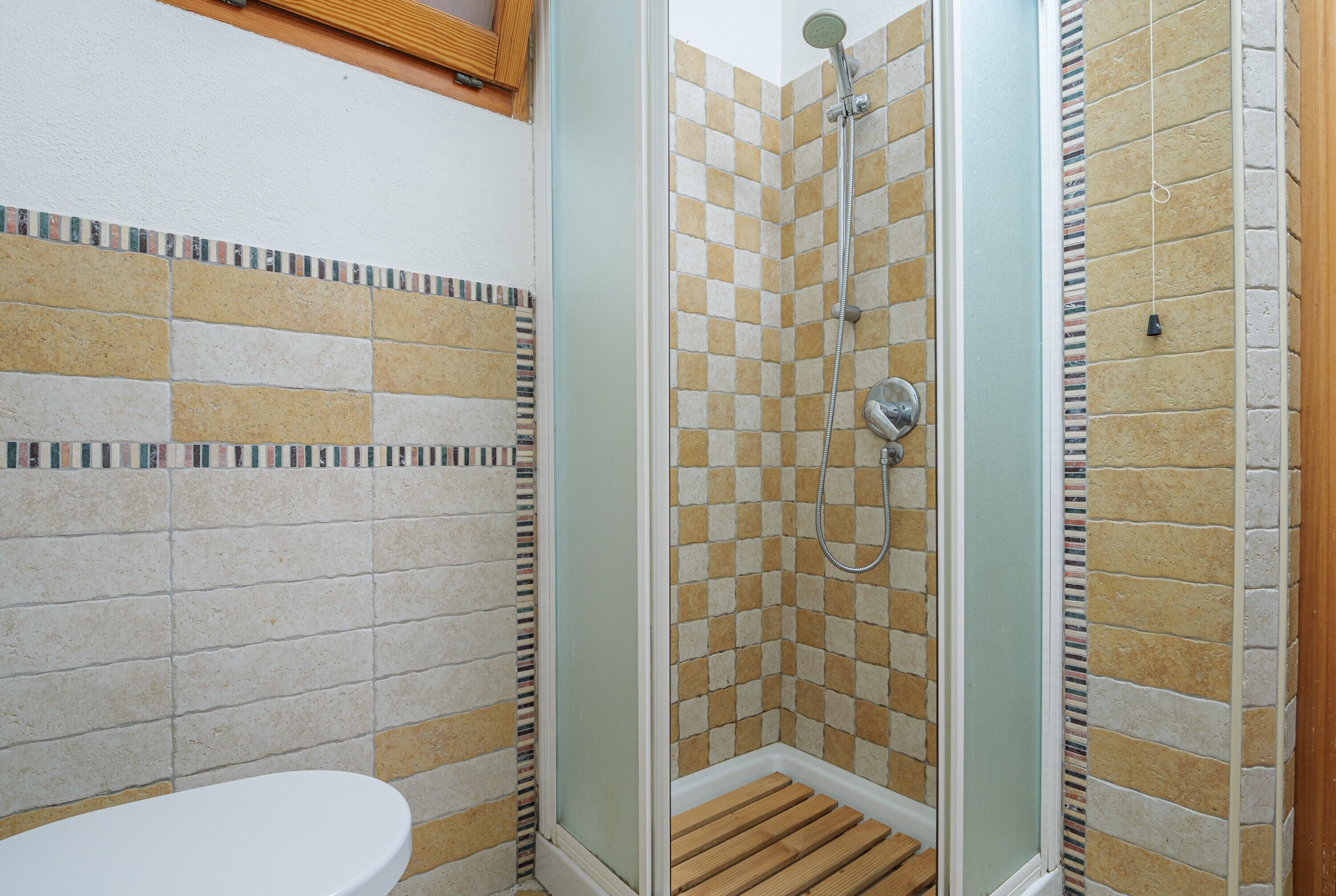 Une salle de bain avec douche, toilettes et murs carrelés.