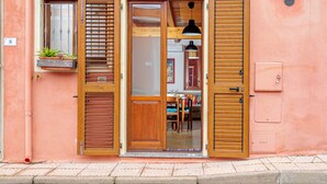A building with a wooden door, a window with a plant, and a light fixture. - Holiday Home 'Porto San Paolo A 50 Mt Dal Mare' with Private Terrace, Wi-Fi and Air Conditioning (Porto San Paolo)