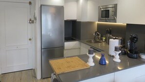 Una cucina moderna con elettrodomestici in acciaio inossidabile, un tagliere in legno e un lavello.