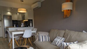 Un soggiorno moderno con un divano beige, sedie bianche, un tavolino rotondo e un'area pranzo con un tavolo e sedie bianche.