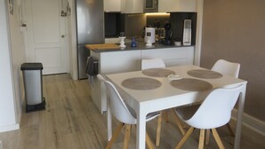 Una cucina moderna con isola centrale, tavolo da pranzo bianco con sottopiatti e un cestino per i rifiuti.