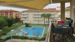 Un balcone con piscina, area salotto esterna e vista su un edificio a più piani.