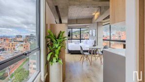 Ein modernes Hotelzimmer mit großem Fenster, einem Bett, einem Esstisch und einem Blumentopf.
