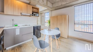 Eine moderne Küche mit grauen Schränken, einer weißen Arbeitsplatte und einem eingebauten Geschirrspüler. Ein runder Esstisch mit zwei Stühlen und ein Blumentopf stehen in der Ecke.
