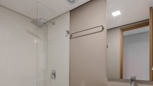 Une salle de bain moderne avec une douche à parois de verre, des toilettes blanches et un meuble-lavabo en bois avec un miroir.