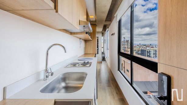 A modern kitchen with a large window, stainless steel sink, and wooden cabinets. - NOK Modern 1BR Apartment at Usaquen Bogota (Bogotá)