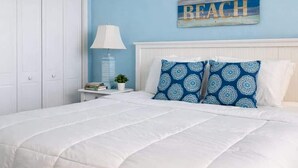 A bedroom with a white bed, blue walls, and a 'BEACH' sign on the wall. - Spacious Beachfront 3br, 2ba Condo in Cherry Grove (Myrtle Beach)
