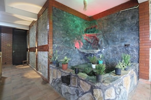 A stone wall with a water feature and potted plants. - Dimuthu homestay  (Ella)