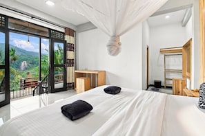 A bedroom with a large bed, a wooden nightstand, a desk, and a view of a mountainous landscape. - Dimuthu homestay  (Ella)