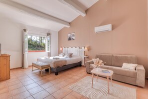 A bedroom with a bed, bedside tables, a sofa, and a window with curtains. - La Maison Du Castellet (Le Castellet)