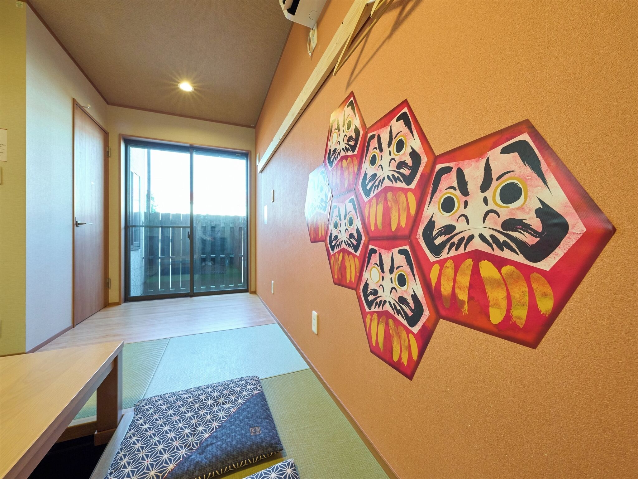 Ein Zimmer mit Tatami-Matten, einer Schiebetür und einer Wand mit traditioneller japanischer Kunst.