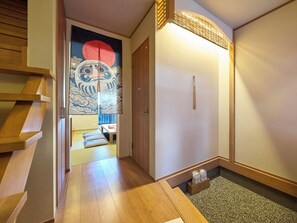 Una habitación japonesa tradicional con suelo de tatami, puertas correderas y un panel shoji con un diseño de círculo rojo.