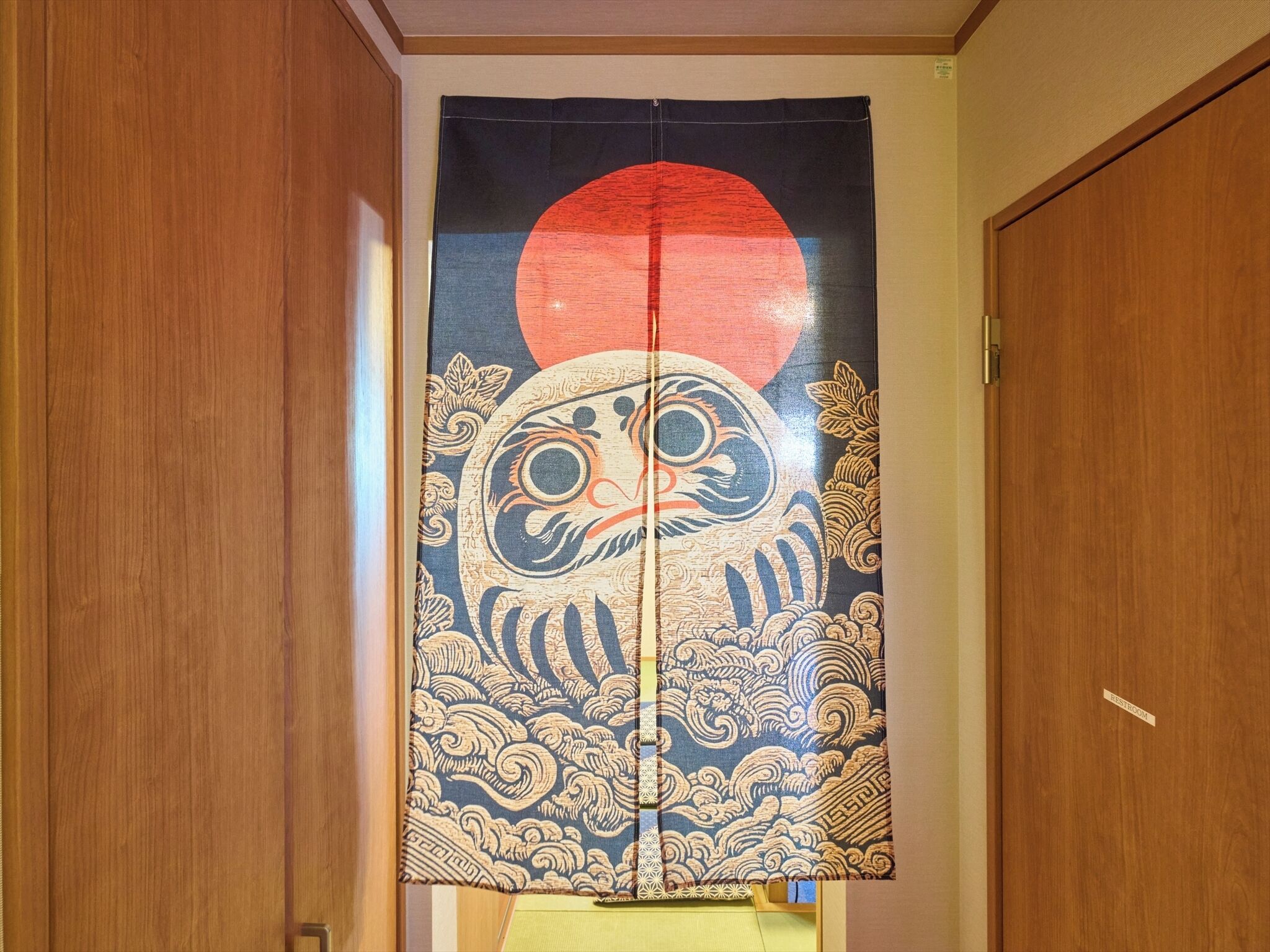 A traditional Japanese room with a tatami mat floor, a shoji screen door, and a sliding door with a red sun emblem.