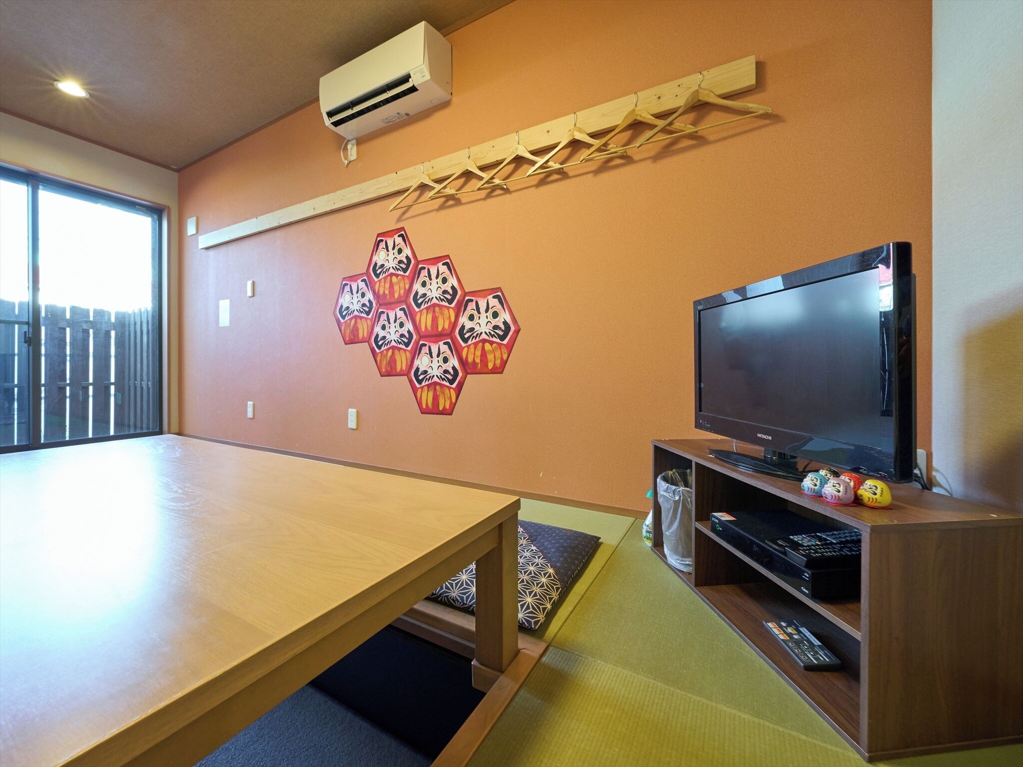 Una habitación con una mesa de madera, un televisor montado y un adorno de pared con formas hexagonales.